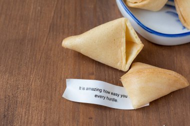 Top view of open fortune cookie with message, on wooden table, horizontal, with copy space