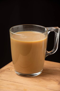 Sütlü cam kahve bardağının yakın plan, ahşap masa, koyu arka plan, dikey, fotokopi alanı