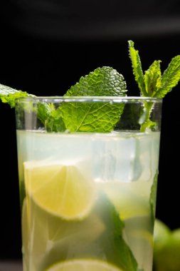 Buzlu, limonlu, nane ve limonlu, siyah arkaplanlı mojito kokteyli ile yakın plan cam.