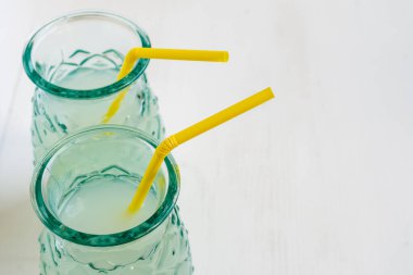 Sarı pipetli iki bardağın üst görüntüsü, seçici odak, beyaz masa, yatay, kopyalama alanı olan