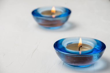 Beyaz masa üzerinde yanan iki mavi cam mum üst görünüm, seçici odak, yatay, kopyalama alanı ile