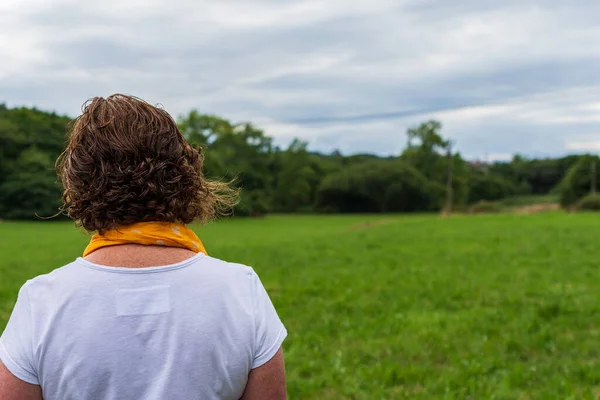 Arkadan beyaz giyinmiş, çözünmüş yeşil alan arkaplanı olan, yatay ve kopyalama alanı olan olgun bir kadın görüntüsü