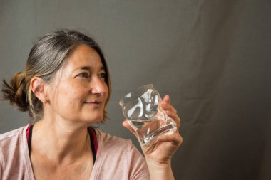 Gülümseyen olgun bir kadının yakın çekimi, spor giysi ve bir bardak su, yoga yaptıktan sonra, portrede, fotokopi alanı ile