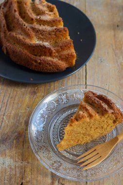 Yarı yoğurtlu kekin havadan görünüşü şeffaf tabakta, ahşap çatalla, tahta masada, dikey