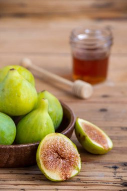 İncir ve bal dolu ahşap tabağı yakın plan, seçici odak, tahta masa, dikey