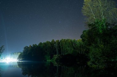 Ormandaki gece göleti, yıldızlar, sonbahar ağaçları, köprüdeki parlak tören, manzara.