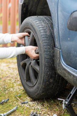 Manikürlü bir kız arabanın tekerleğini değiştirir, kriko, İngiliz anahtarı, kayganlaştırıcı. yakın plan.