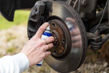 Manikürlü bir kız arabanın tekerleğini değiştirir, kriko, İngiliz anahtarı, kayganlaştırıcı. yakın plan.