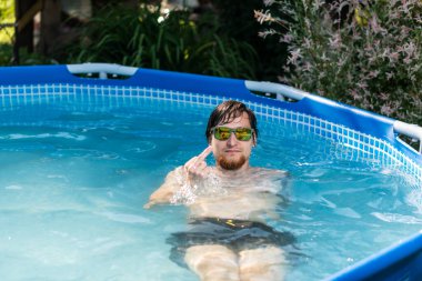 Man in glasses in the summer in a blue pool showing middle finger doing fuck you bad expression, provocation and rude attitude.