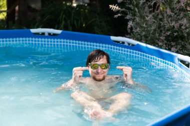 Man in glasses in the summer in a blue pool showing middle finger doing fuck you bad expression, provocation and rude attitude.