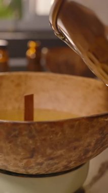 Dikey video. Erimiş Balmumu 'nun son damlaları Gümüş Saksıdan Hindistan cevizi kasesine düşüyor Yavaş Hareket, Mum Yapımı Hobisi