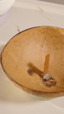 Dikey video. Ahşap fitili olan hindistan cevizi kasesi kehribar cam yağ şişesinin yanına yerleştirilmiş. DIY Craft kavramını kabul et