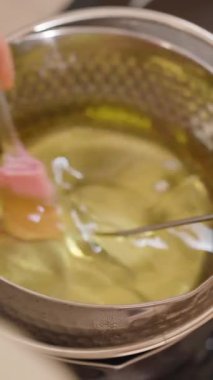 Dikey video. Erimiş soya ağdasının spatulayla karıştırılmasının en üst görüntüsü sıcaklığın dijital termometreyle ölçüldüğü kabın içinde. DIY Craft kavramını kabul et