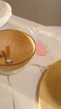 Dikey video. Gün batımı ışığı, mum yapımı malzemeleri, kehribar şişeleri, balmumu torbası, hindistan cevizi kaseleri ve geniş açı. Kavramsal Konforlu Ev Dekoru