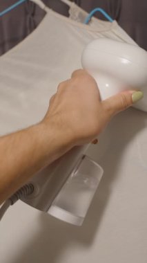 Dikey video. Birinci Şahıs Görünümü: Buharlı Buharlı El Giysisi Buharlı, Kapalı, Kapalı, Yavaş Çekim, Ev İşleri Konsepti