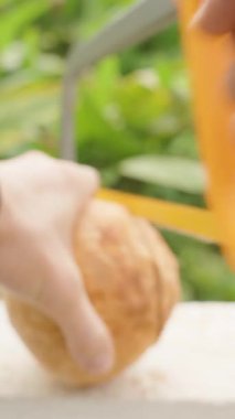 Dikey video. Açılış için hindistan cevizi kabuğunu delmek için Sarı El Aracı kullanan, Beton Duvarı sıkıca kavramış, İlk Kişi Açısı, Sağlıklı Yeme Konsepti