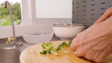 Bright Kitchen 'daki Ahşap Kesme Tahtasında Arka planda Lavabo ile Yavaş Çekim Brokoli Kesimi