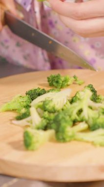 Dikey video. Mutfaktaki Yuvarlak Ahşap Kesme Kurulunda Brokoli Çiçeklerini Görünür Önlükle Yavaş Çekimde Kapat