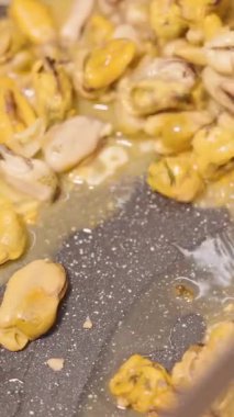 Dikey video. Yavaş Çekimde Sıcak Yağ ve Sarımsak ile Karıştırıcı Tavadaki Midyeleri Kapat