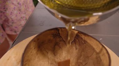 Ilık Altın Balmumu, Metal Pot 'tan Rustik Coconut Shell Bowl' a dökülüyor. İçi Tahta Wick İçerisi, Yavaş Hareket, Yakın Görüş