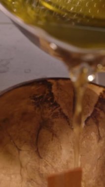 Dikey video. Ilık Altın Balmumu, Metal Pot 'tan Rustik Coconut Shell Bowl' a dökülüyor. İçi Tahta Wick İçerisi, Yavaş Hareket, Yakın Görüş