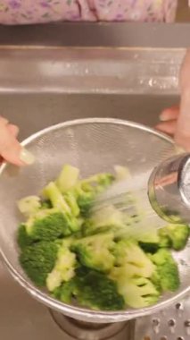 Dikey video. Colander Under Kitchen Musluğu 'nda Buharlı Brokoli Buharlı Kadın Görünümü, Parlak Kapalı Su, Sağlıklı Yaşam Konsepti
