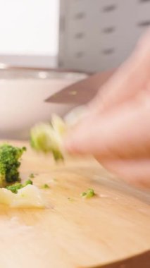 Dikey video. Yuvarlak Tahta Tahtadaki El Dilimleme Brokolisinin Kapanışı Pencere Doğal Işığı Sağlıklı Mutfak Konsepti