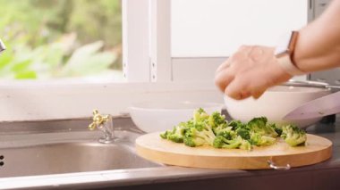 Ön planda Bıçakla Kolander 'a Doğramalı Brokoli Yerleştiren Kadın Arka Görünümü, Arkaplanda Lavabo, Sağlıklı Yemek Kavramı