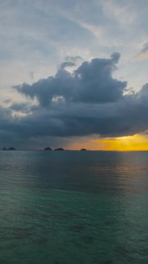 Dikey video. İnsansız Hava Aracı, Kara Bulutlar ve Işığın Geniş Hava Görünümü ile Ufuk 'ta Gün batımına doğru ilerliyor.