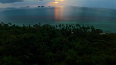 FPV İnsansız Hava Aracı, Palmiye ağaçlarının arasından hızla iniyor Turkuaz Suya ve Ufuk Açısında Altın Günbatımı Yansıması Geniş Açı Hava Çekimi, Aşırı Uçma Konsepti