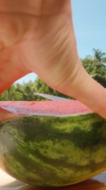 Dikey video. Sunny Outdoor 'da Tahta Yüzeyden Taze Karpuz Kesme ve Kesme Mavi Gök ve Yeşil Ağaçlar, Taze Meyve Konsepti