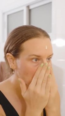 Dikey video. Parlak Banyo 'da Parlak Banyo' da Kadın Yüze Krem Sürme, Cilt Konsepti