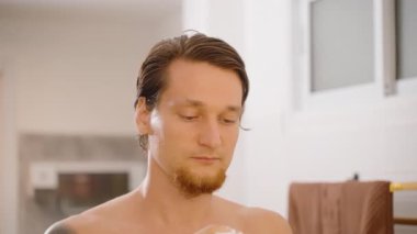 Banyodaki aynada alnına yüz kremi süren adam, yakın açı, erkek cildi kavramı.