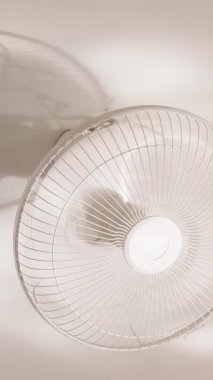 Dikey video. Görünür Gölge ve Güneş Işığı Yansımaları ile Duvara monte edilen Tavan Kapalı Pervane, dar açılı çekim, Kapalı Salon Soğutma ve Hava Dolaşım