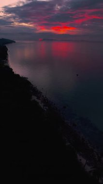 Dikey video. Şehir Işıkları ve Okyanus Üzerindeki Pembe Bulutlar ile Deniz Kıyısı Görünümü, Kıyı Akşamı Manzarası Konsepti