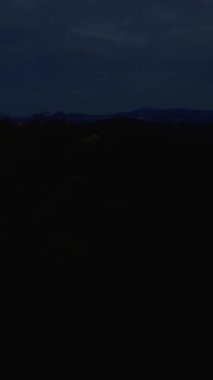 Dikey video. FPV İHA 'sı Rocky Kıyı Şeridi' nde Kızıl Günbatımı Yansımaları ile Karanlık Okyanusa dalıyor, Sinema Macerası Konsepti