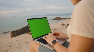 Yeşil Ekranlı Dizüstü Bilgisayarda Çalışan Ocean View ile Sahilde Oturan, Geniş Açı Uzaktan Çalışma Konsepti