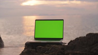 Yeşil Ekranlı Laptop Okyanus Tarafından Kayaya Yerleştirilmiş Günbatımı Yansıması, Geniş Açı, Doğa ve Teknoloji Konsepti