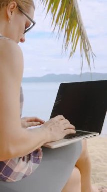 Dikey video. Mavi Okyanus Uzaktan Kumandalı Kumsalda Yaşam Tarzı ile Kum Kumsalında Otururken Dizüstü Bilgisayarda Daktilo Yazan Kadının Kapanışı