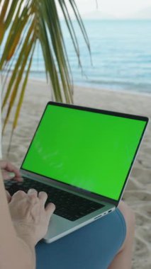 Dikey video. Palm Leaves Geniş Açı, Uzaktan Çalışmalar ve Dijital Göçebe Konsepti ile çevrili Yeşil Ekran Bilgisayarlı Kum Kumsalında Oturan Kişi