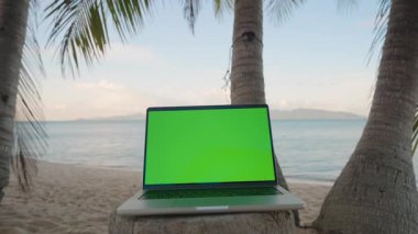 Arka plan Çekimi, Dijital İş ve Seyahat Konseptinde Okyanus Ufkunu ile Palmiye Ağaçları Arasında Yeşil Ekran Yakından Görünümlü Laptop