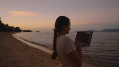 Akşam Alacakaranlığı, Uzaktan Çalışma Konsepti boyunca Okyanus kenarında Dizüstü bilgisayarda çalışan Uzun Braid 'li Kadın