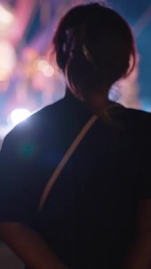 Dikey video. Parlak Işıklar ve Sahne Alanıyla Sahne Arkasından Canlı Müzik Konseri İzleyen Kadın