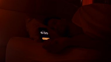 Beyaz çarşafların altında yatıp sabah 6 'da alarmı kapatıp pencereden dışarı bakan ve ılık loş sabah tembelliği içinde yuvarlanan bir adam.