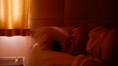 Smartphone 'da 6: 00 Alarmı Kapatılan Gözler Sabah Gevşemeden Önce Parlak Işıkla Pencereye Bakan Kadın