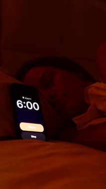 Dikey video. Sabah 6 'da Smartphone' da Uyuyan Kadın Alarmı kapatıp Sabah Uykusuzluğu 'na geri dönmeden önce Parlak Pencere' ye bakıyor