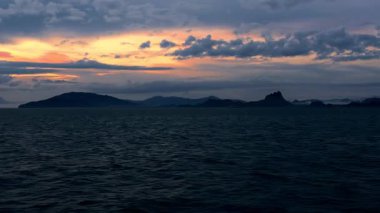 Moving Ship on Calm Sea During Sunrise with Cloudy Sky and Silhouetted Islands on Horizon Tranquil Morning Journey