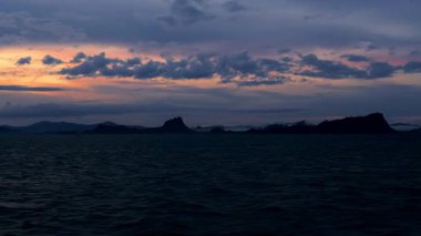 Early Morning Sunrise Over Sea Seen from Moving Ship with Distant Dark Islands and Glowing Clouds Peaceful Voyage