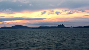 Golden Sunrise Over Calm Ocean Seen from Deck of Moving Ship with Mountain Islands on Horizon Morning Serenity