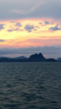 Vertical video. Golden Sunrise Over Calm Ocean Seen from Deck of Moving Ship with Mountain Islands on Horizon Morning Serenity
